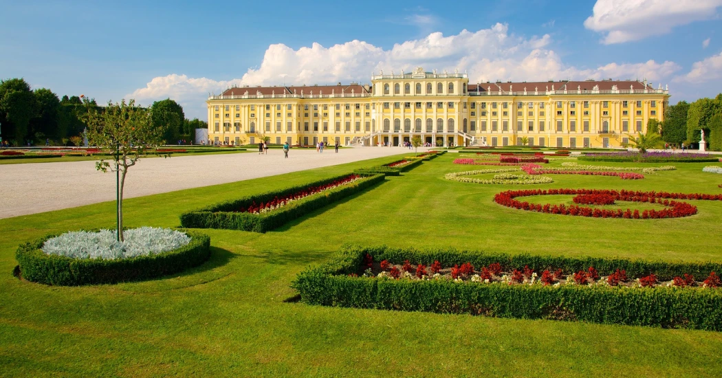 Beautiful green garden with colorful flowers in front of Schonbrunn Palace.