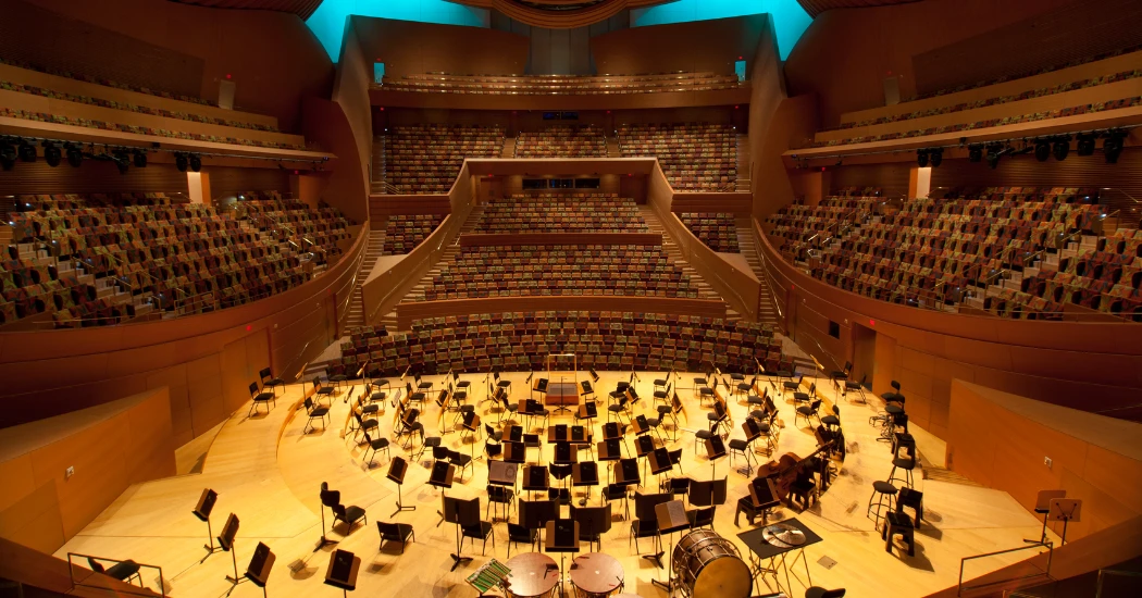 A whole scene of sitting and a stage inside a big hall. 