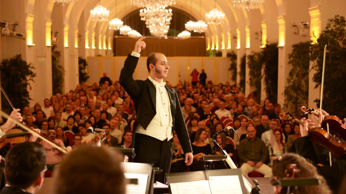 A concert taking place with orchestra and audience in the background.