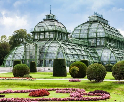 A large, glass-paneled structure with a curved roof, surrounded by lush gardens and greenery.