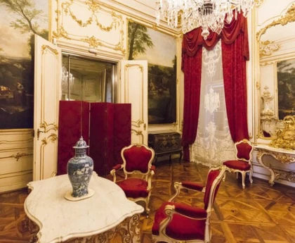 A well-decorated red color theme royal room with antique chairs, tables, and curtains. 