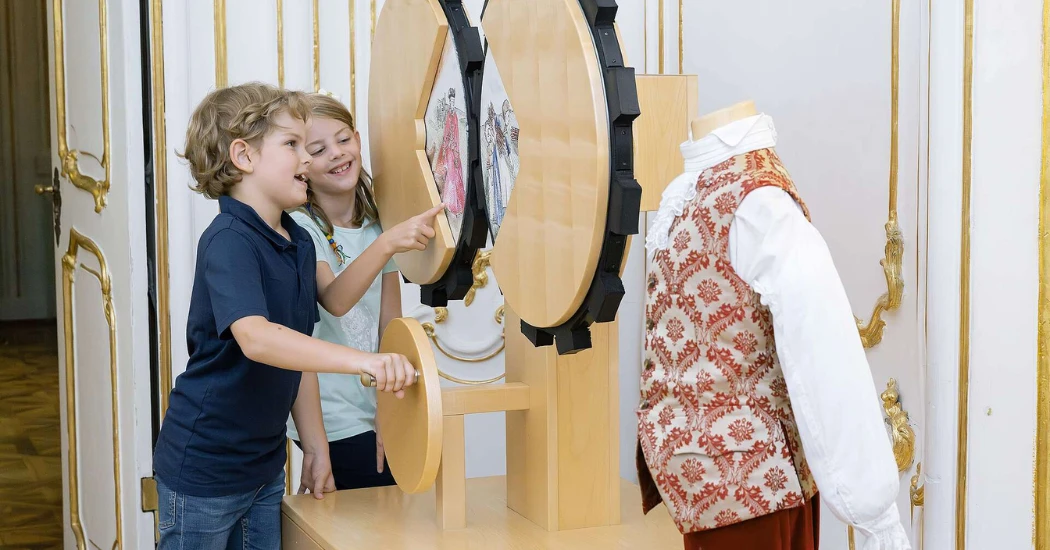 Children exploring historical costumes at an interactive museum exhibit.
