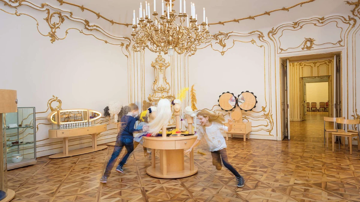 Interactive museum room with kids exploring historical costumes and accessories.
