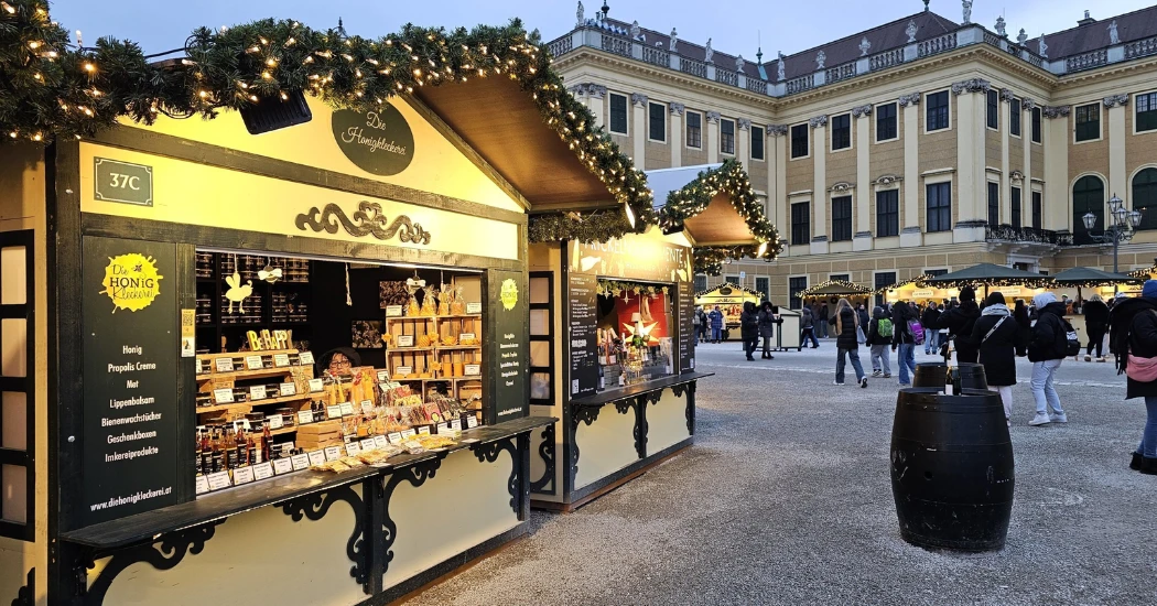 Christmas market stalls at Schönbrunn Palace selling honey and handmade gifts.