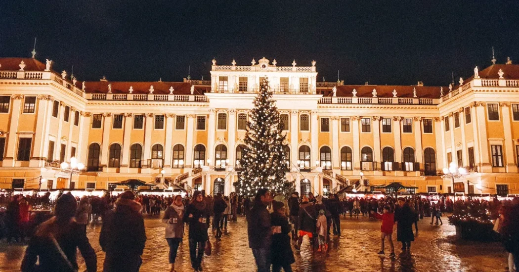 Glowing Christmas tree surrounded by visitors at Schönbrunn Palace Vienna.