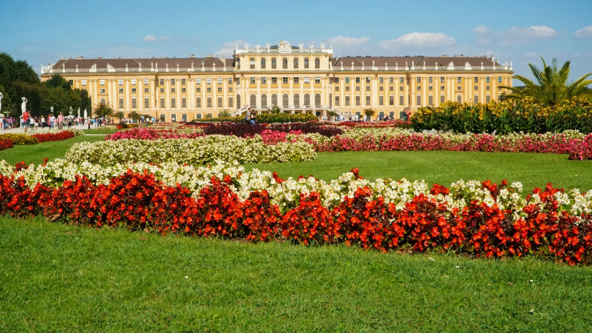 Colorful flower beds in the foreground with the grand Schönbrunn Palace in the background.